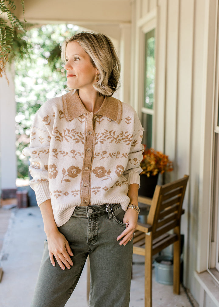 Model wearing a cream sweater with tan flowers, buttons, long sleeves and a tan collar.