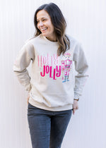 Model wearing a cream long sleeve sweatshirt with a nutcracker and holly jolly written in pink