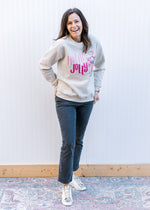 Model wearing black jeans and a cream sweatshirt with a nutcracker and holly jolly written in pink