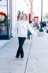 Model wearing a mocha oversized sweater with a mock neck, long sleeves and split sides.