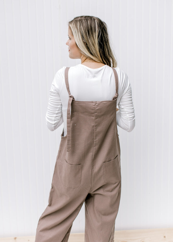 Back view of a model wearing an ivory long sleeve bodysuit with a mocha jumpsuit. 