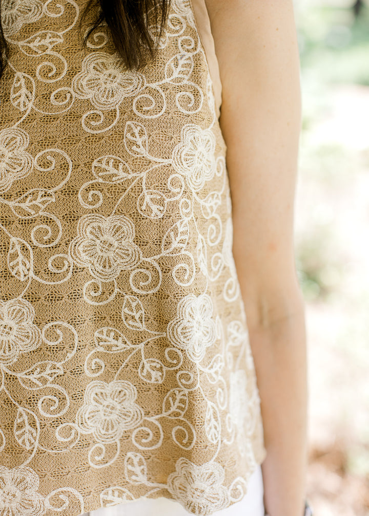 Close up of cream stitching on a camel colored sleeveless blouse with a full lining. 