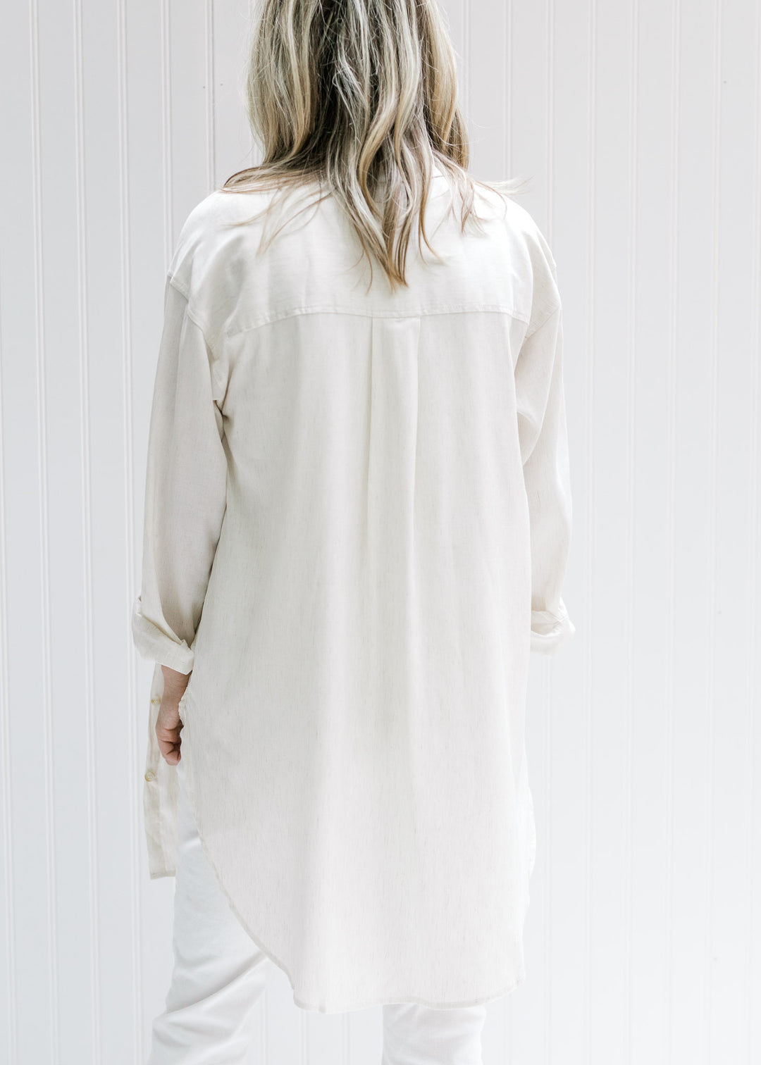 Back view of Model wearing a cream button down top made of a linen blend. 