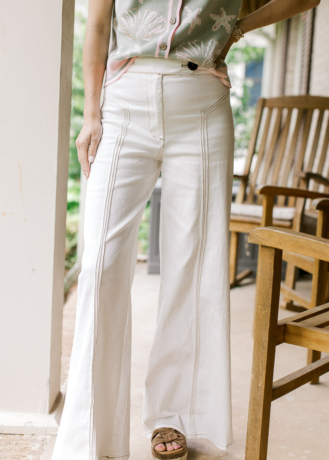 Model wearing creamy denim wide-leg pants with front zip, button and triple seam detail down front.