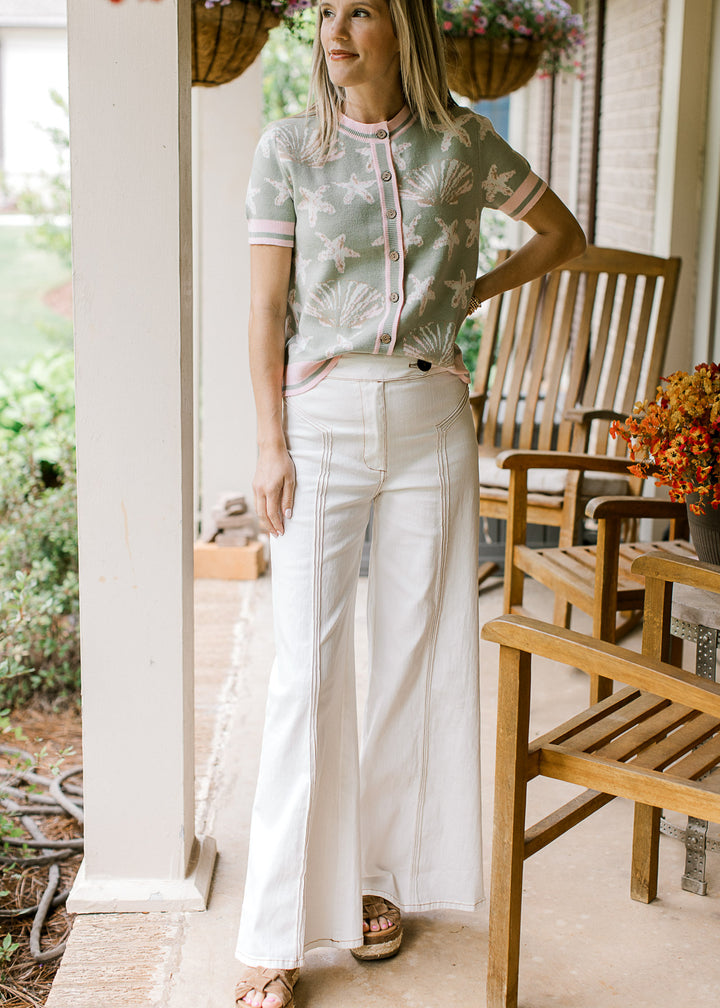 Model wearing sage top and creamy denim wide-leg pants with a triple seam detail down front.