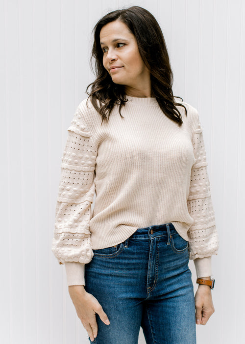 Model wearing a cream sweater with ribbed bodice, textured bubble long sleeves and a round neck. 
