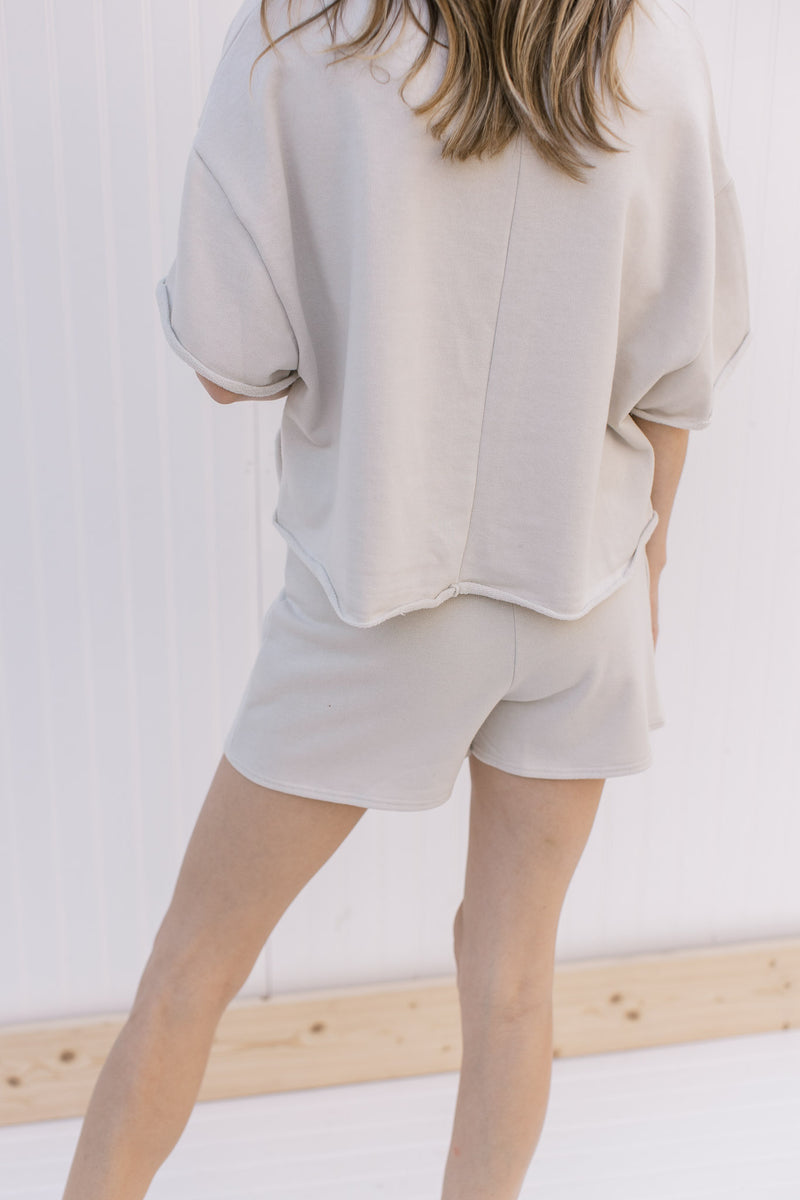 Back view of model wearing a cream skort with exposed shorts in back. 