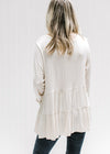 Back view of Model wearing a cream tiered top with long sleeves and composed of bamboo viscose. 