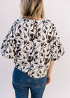 Back view of Model wearing a cream top with a black floral pattern and bubble short sleeves.