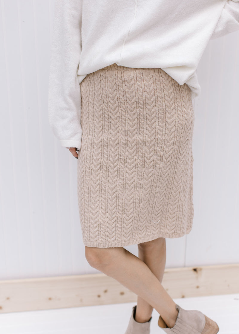 Close up of cable knit on a cream skirt, hitting just above the knee with an elastic waist band. 