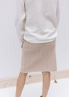 Back view of model wearing a cream cable knit skirt, just above the knee with an elastic waist.