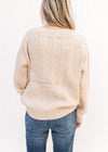 Back view of a model wearing a cream cable knit sweater with long sleeves and acrylic material. 