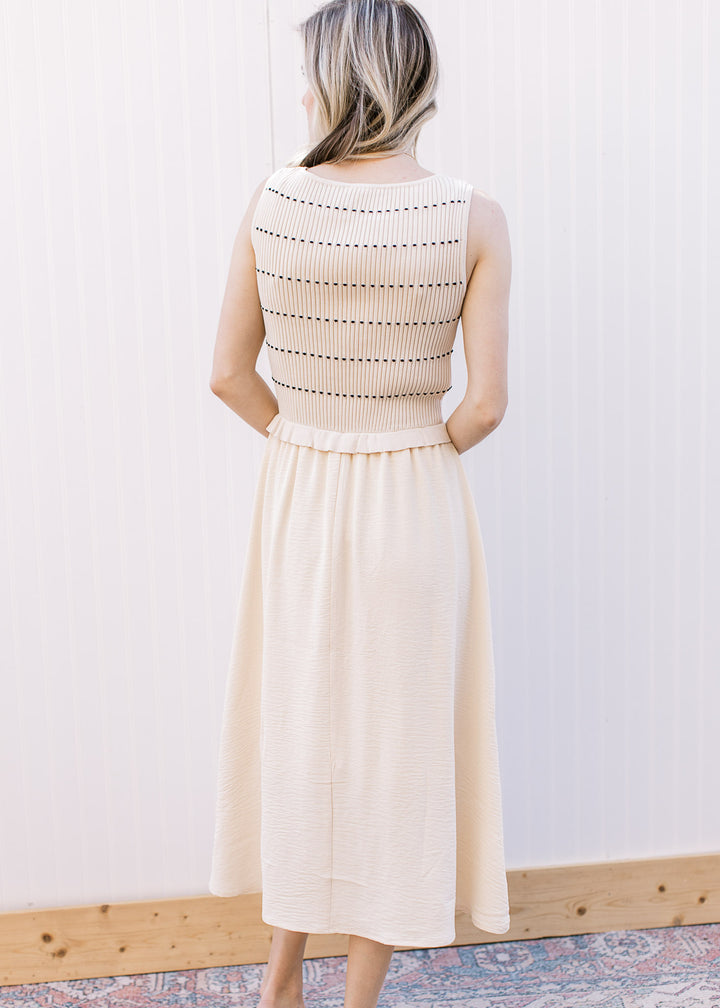 Back view of Model wearing a cream midi with attached sleeveless ribbed sweater with black stripes.