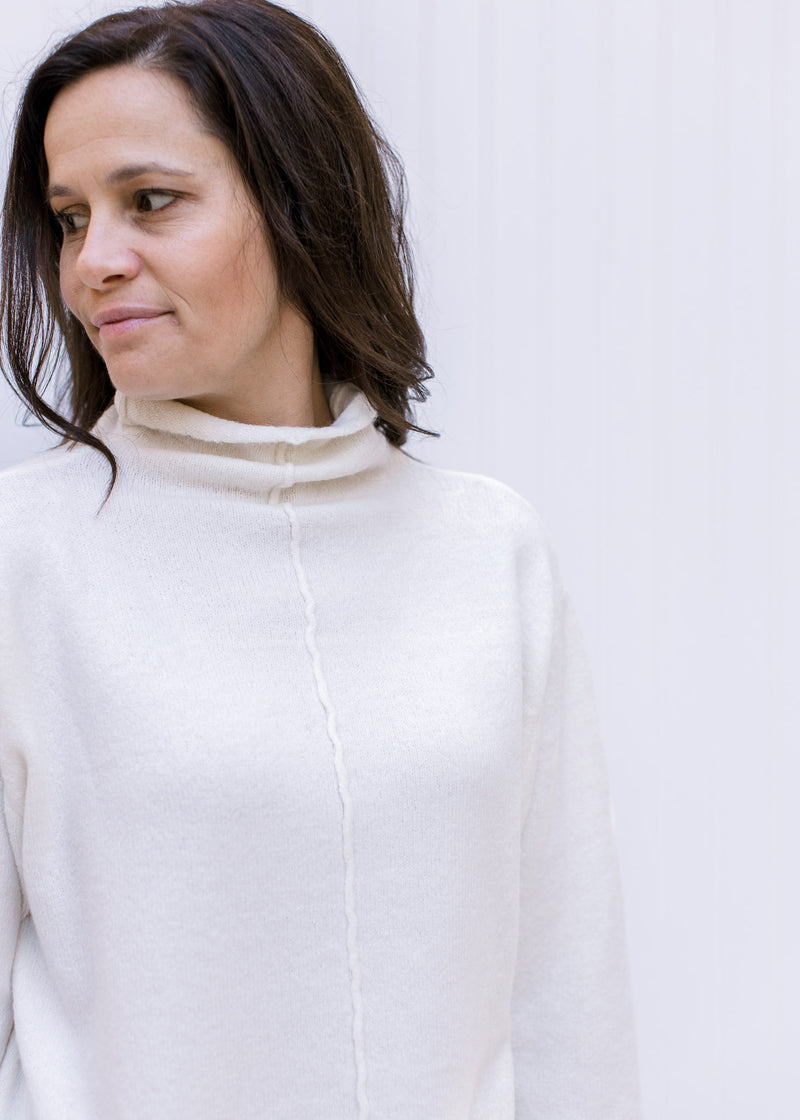Close up of turtleneck on a cream sweater with long sleeves and a cozy, stretchy sweater. 