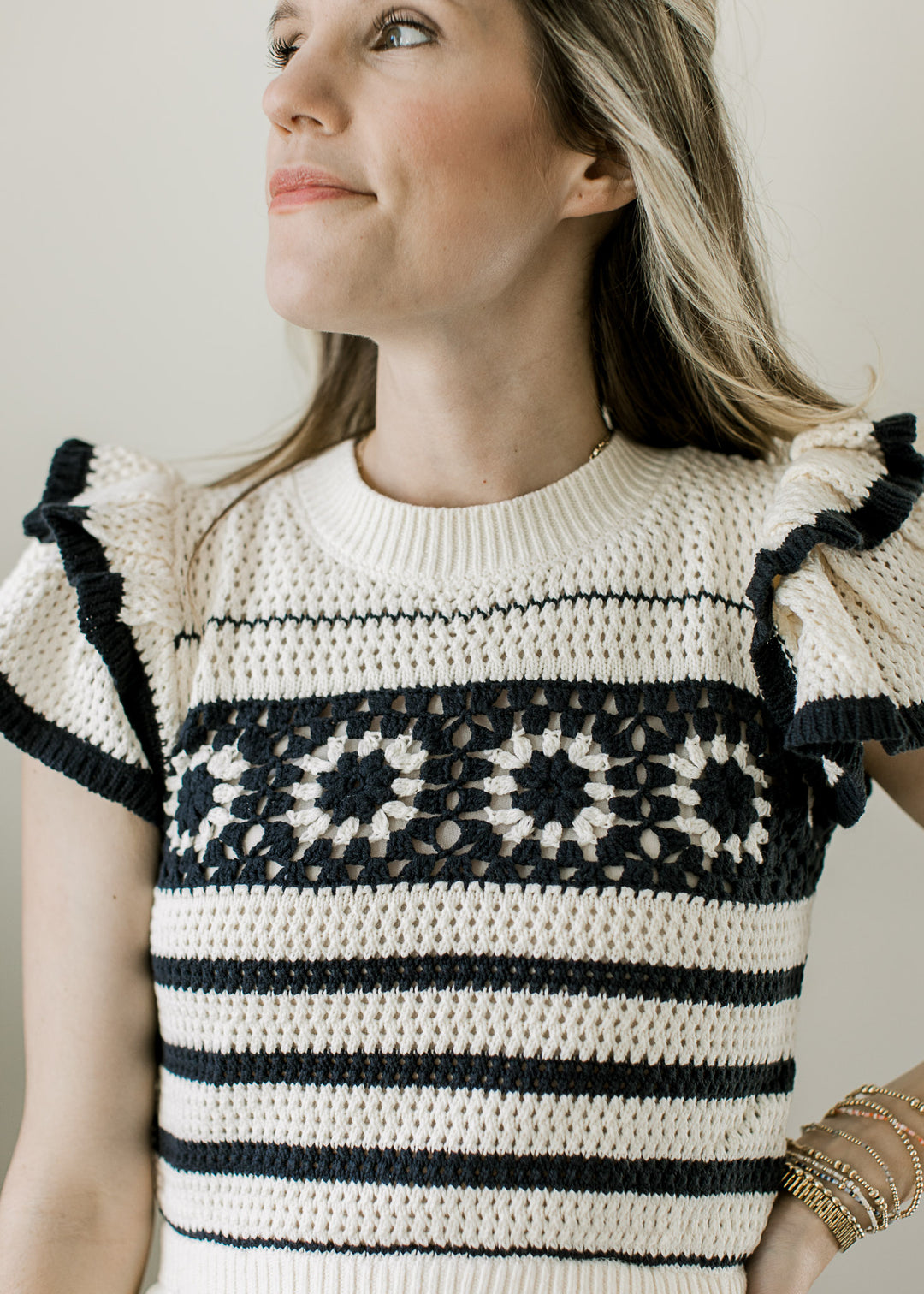 Close up of crochet sweater with flutter cap sleeves with black stripes and one floral stripe. 