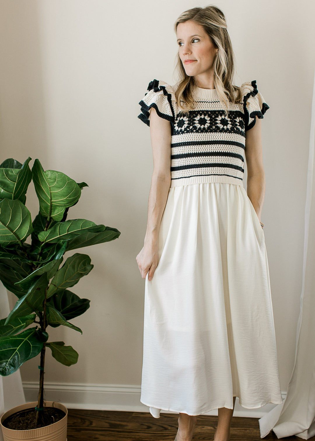 Model wearing wedges and a cream skirt with attached crochet sweater top with black stripes.