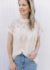 Model wearing a cream short sleeve top with an open diamond weave and capped sleeves.