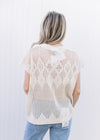 Back view of Model wearing a cream short sleeve top with an open diamond weave and capped sleeves.