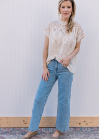 Model wearing jeans, flats and a cream short sleeve top with an open diamond weave. 