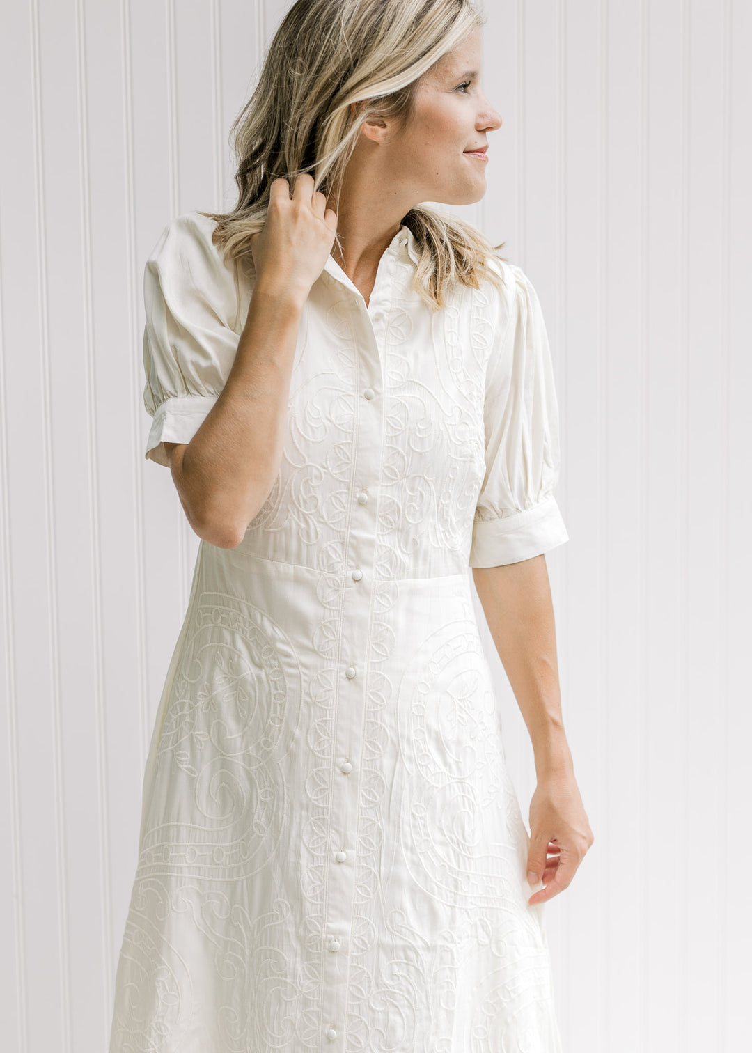 Model wearing a cream midi dress with a button closure, scalloped neck and short sleeves. 