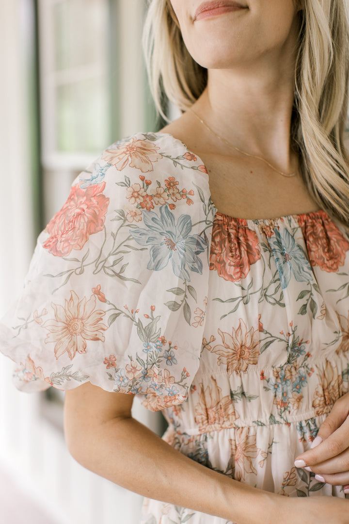 Close up of bubble short sleeves on a cream floral dress with a square neck and smocked bodice. 