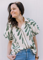 Model wearing a lightweight cream top with olive print, bubble short sleeves and a collar. 