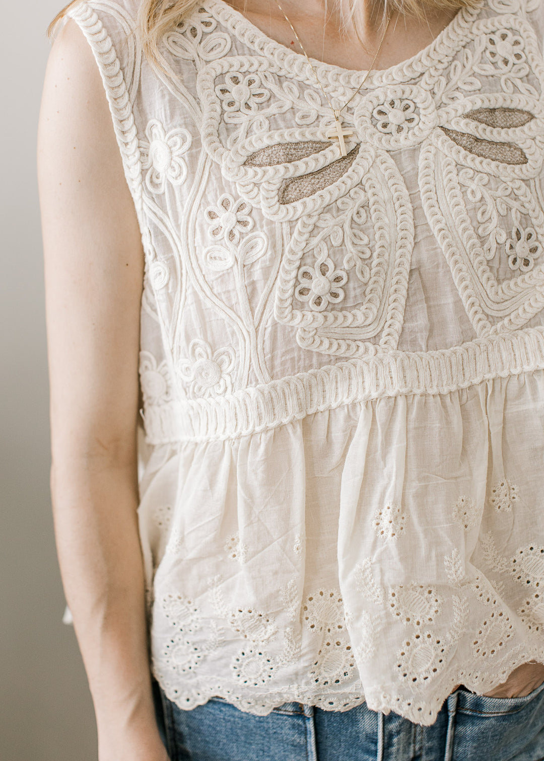 Close up of crochet floral front on a sleeveless top with scalloped hem and eyelets.