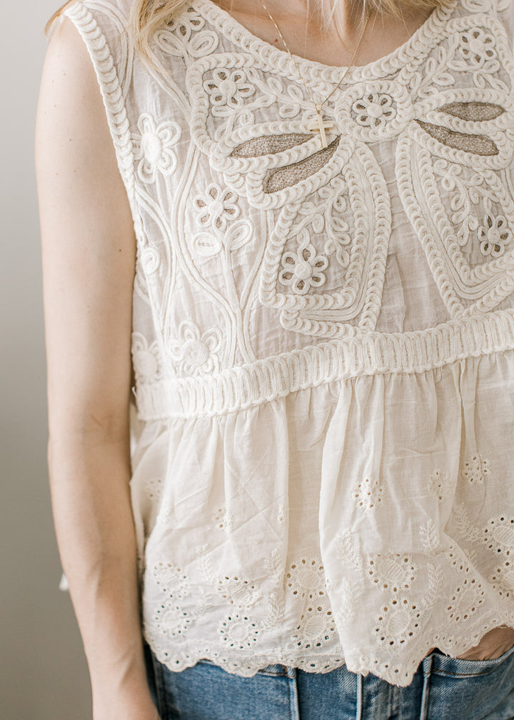 Close up of crochet floral front on a sleeveless top with scalloped hem and eyelets.