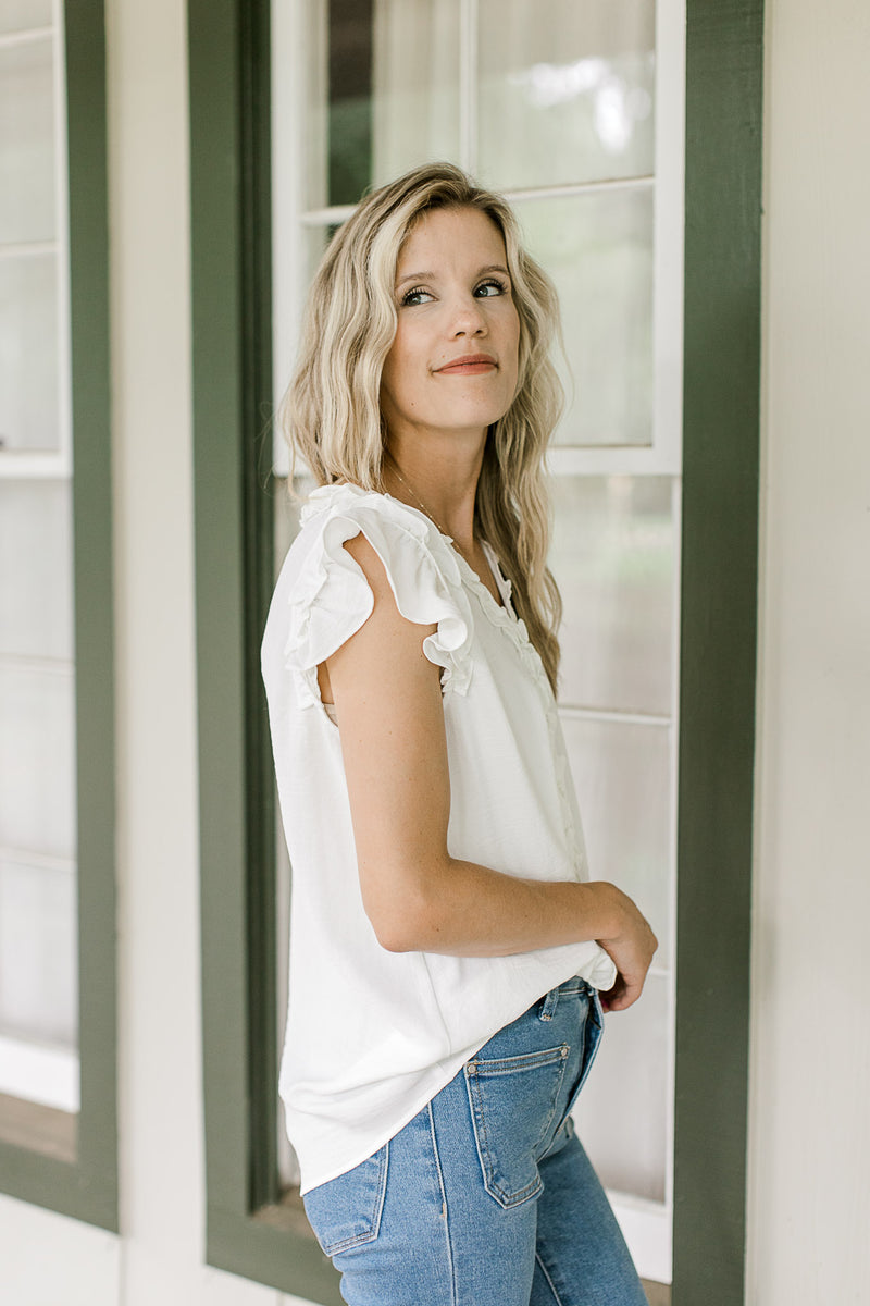 Side view of ruffle cap sleeve on a white top with a ruffle v-neck and placket