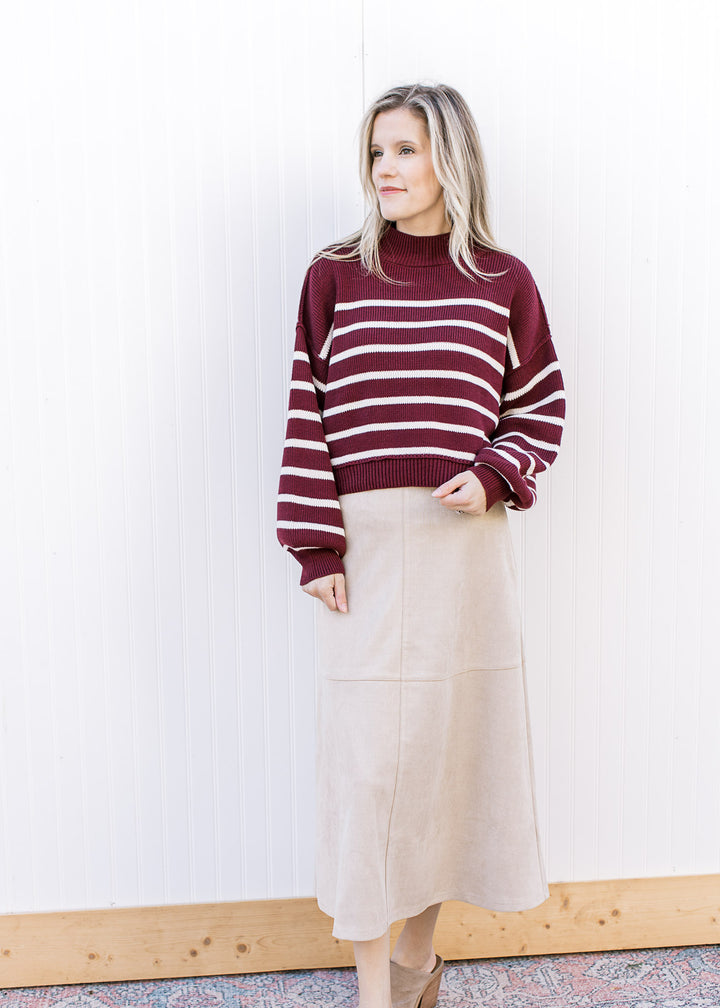 Model wearing a burgundy sweater and a cream-tan suede midi with a hidden side zipper with clasp.