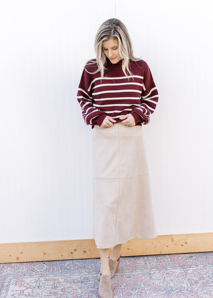 Model wearing a burgundy sweater, booties and a cream suede midi with a hidden side zipper.
