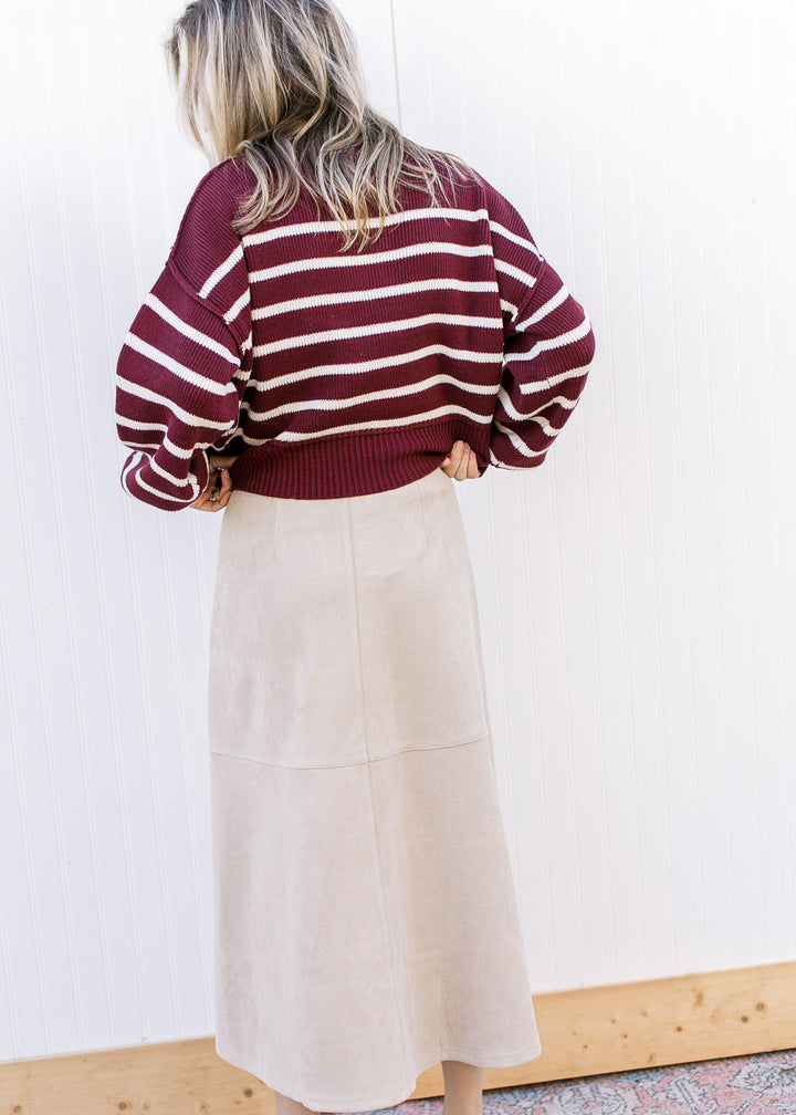 Back view of Model wearing a burgundy sweater and a cream suede midi with a hidden side zipper. 
