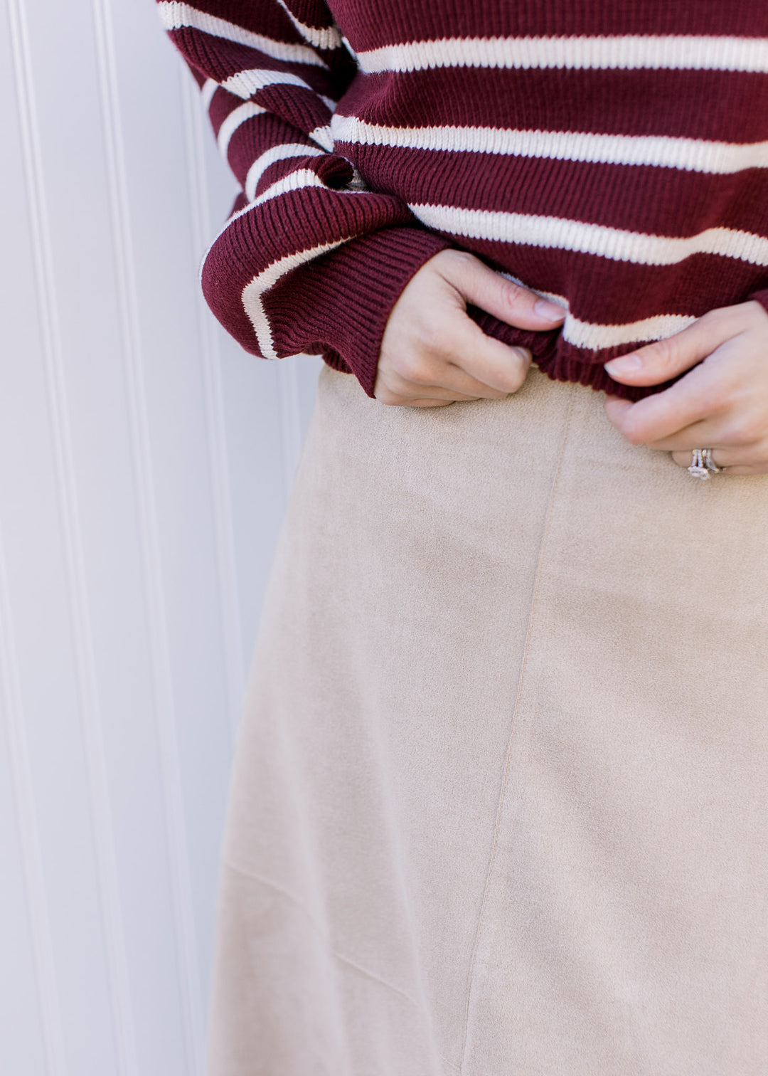 Close up of seam on a creamy-tan suede midi with a hidden side zipper with a clasp. 