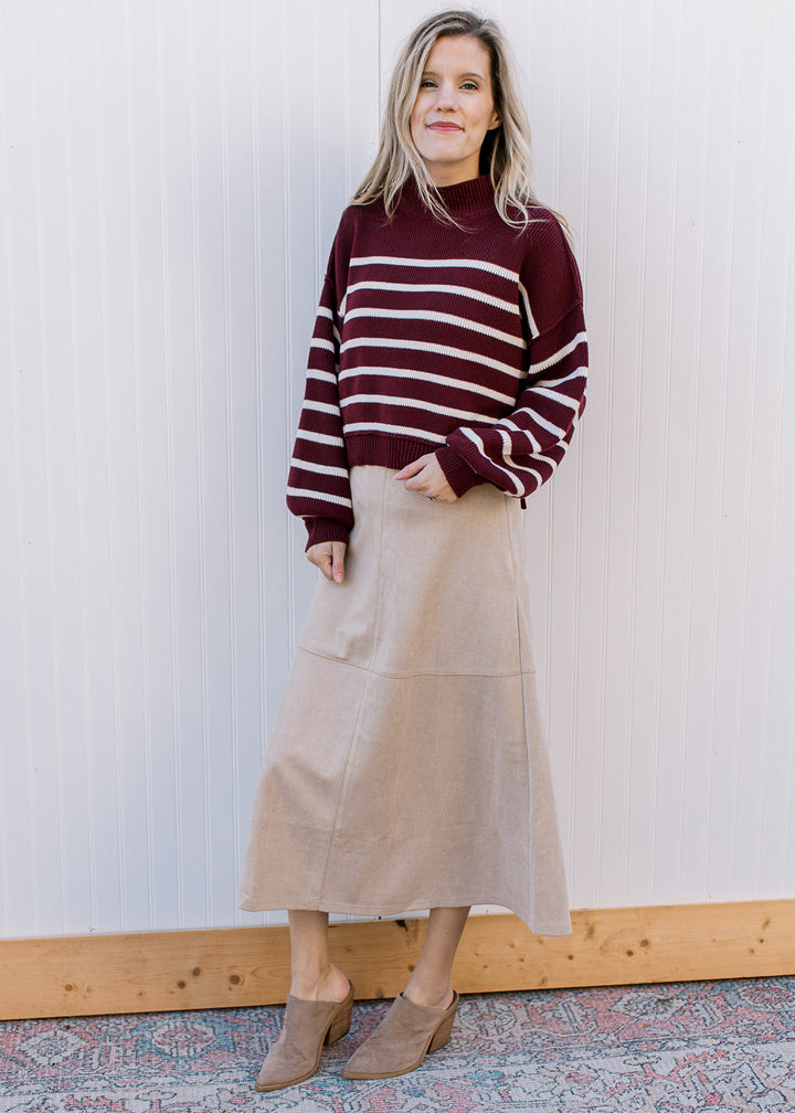 Model wearing a burgundy sweater, heels and a cream-tan suede midi with a hidden side zipper.