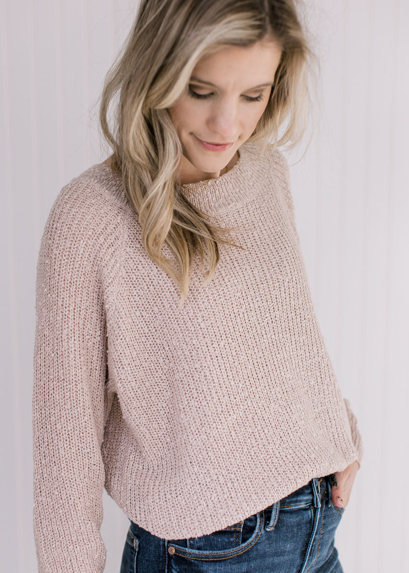Close up of popcorn knit on a cream colored sweater with long sleeves and a round neck. 