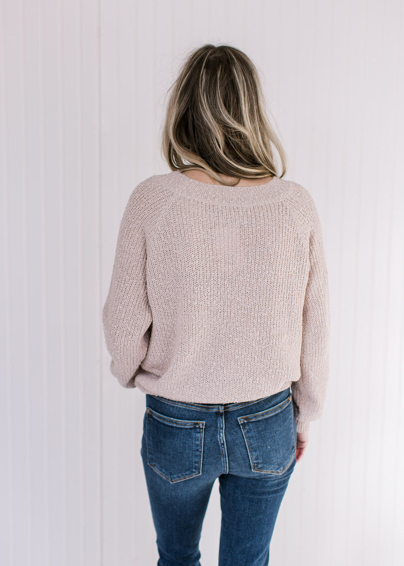 Back view of Model wearing a cream sweater with popcorn knit, round neck and long sleeves.