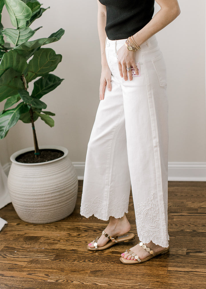 Model wearing a creamy white wide-leg cropped jeans with tone-on-tone embroidery at hem.