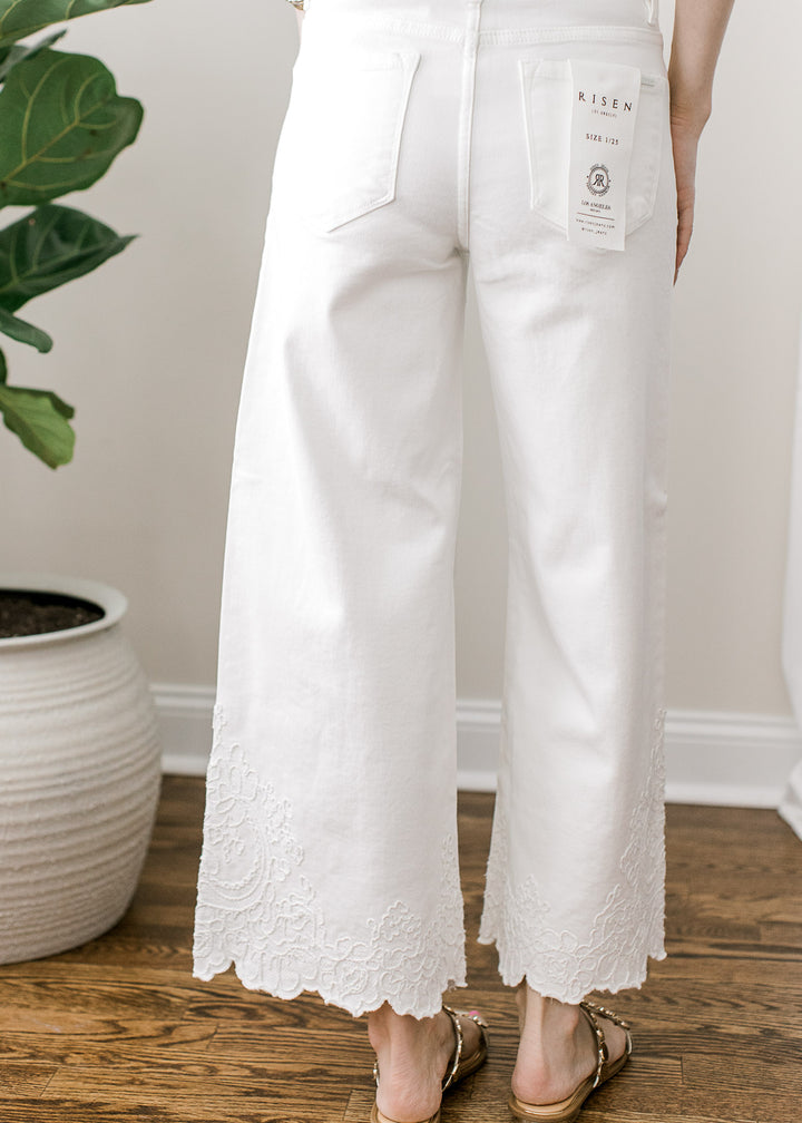 Back view of Model wearing a white wide-leg cropped jeans with tone-on-tone embroidery at hem.