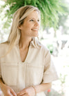 Close up of v-neck, patch pockets and contrast stitching on a cream denim dress. 