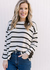Model wearing a ribbed cream sweater with black stripes and a contrasting placket at cuffed sleeve