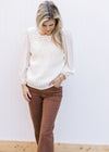 Model wearing brown jeans and a cream top with crochet front and slightly sheer 3/4 sleeves.