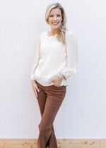 Model wearing a cream top with crochet front, pleated shoulders and 3/4 sleeves. 