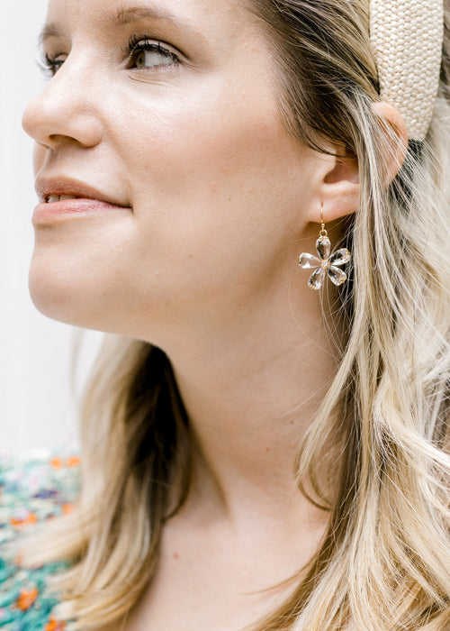 Model wearing a crystal daisy dangle earring with a gold wire. 