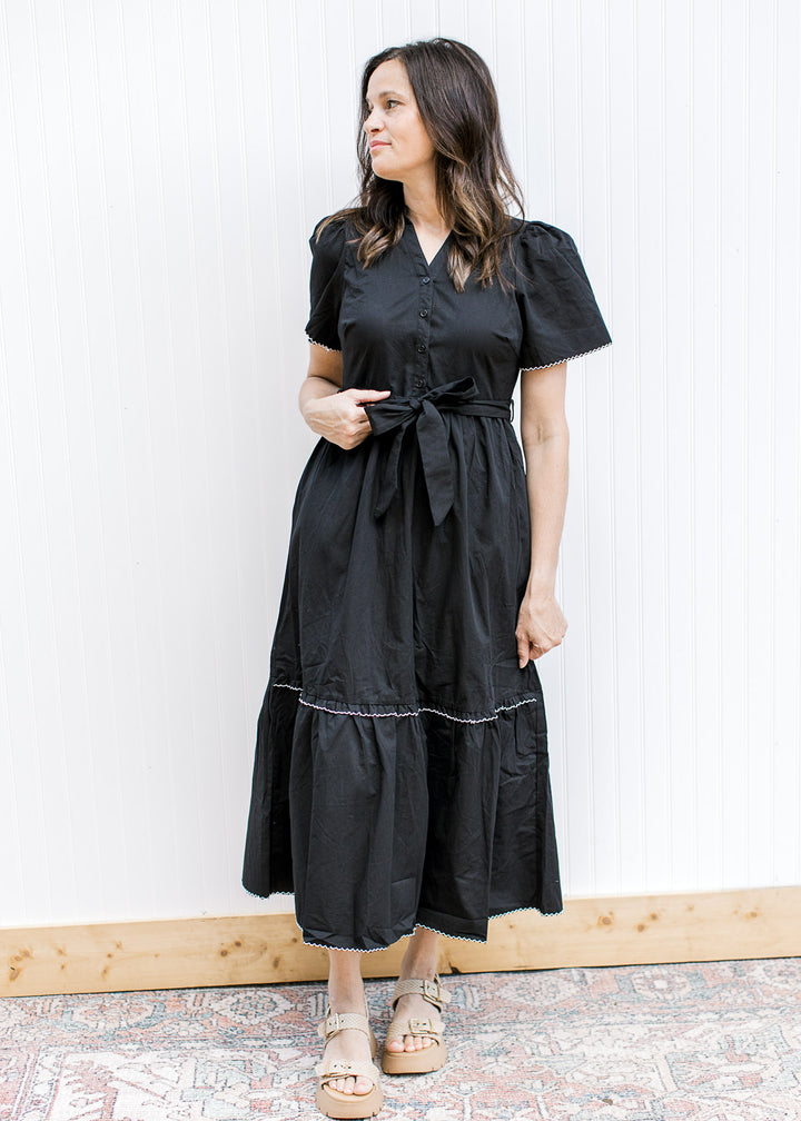 Model wearing a black midi with white trim at tie and cuff is short sleeve and a tie waist.