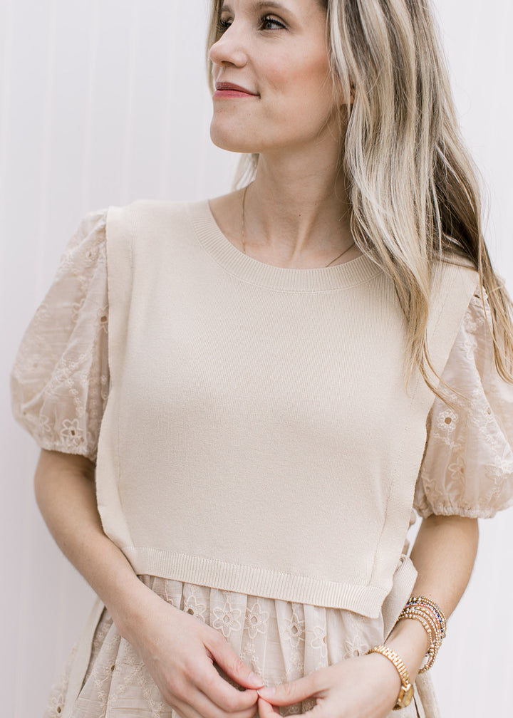 Close up of attached sweater vest on a pale coffee colored above the knee dress with short sleeves.