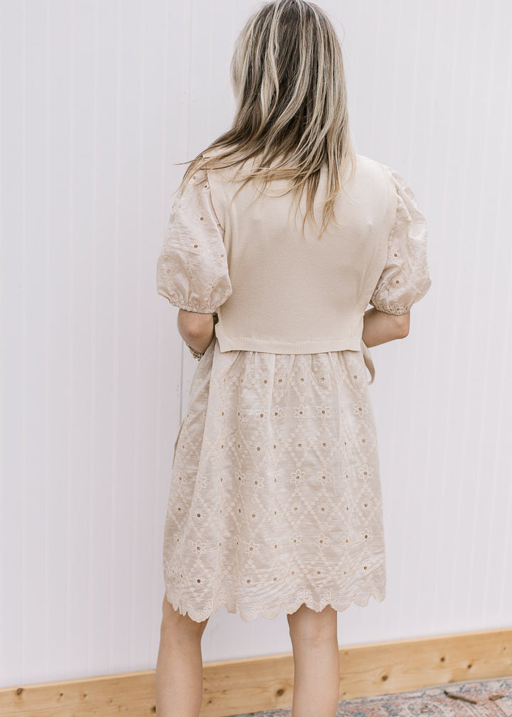 Back view of model in cut lace dress with short sleeves, matching sweater vest and scalloped hem.
