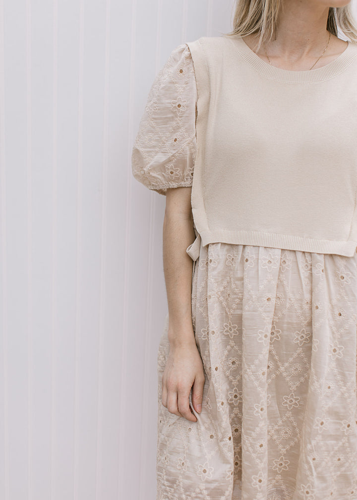 Model wearing a pale coffee cut lace dress with attached sweater vest with side ties. 