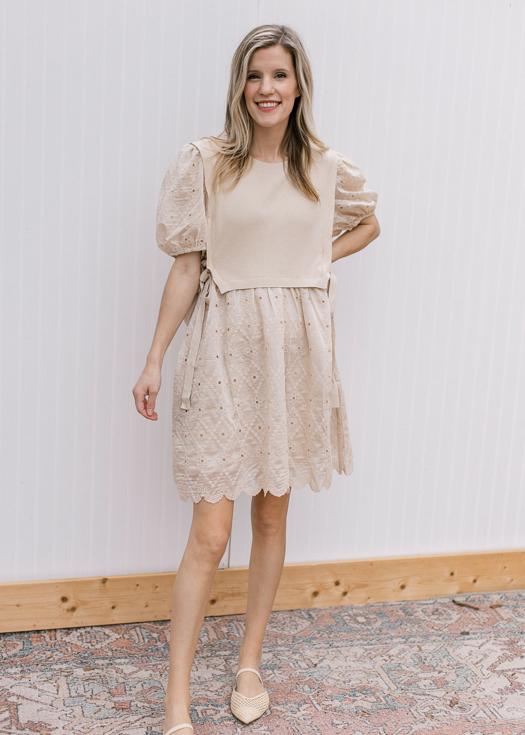Model wearing flats and a pale coffee cut lace dress with attached sweater vest with side ties. 