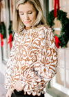 Model wearing a cream and reddish-brown lacework top with an ivory lining and ladder trim at neck. 