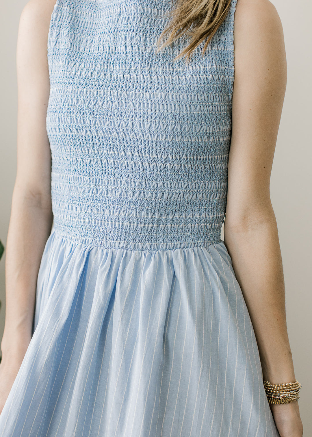 Close up of smocked bodice and white pinstripes on a light blue sleeveless maxi. 